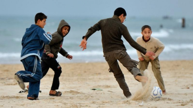 Anak-anak bermain sepakbola di pantai Gaza