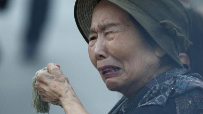 Seorang wanita menangis, mengenang korban serangan bom atom di Hiroshima.