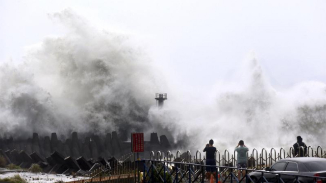 Beberapa orang melihat terpaan gelombang laut akibat topan Soudelor di Taiwan.