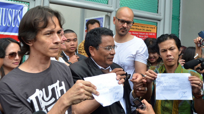 Guru Jakarta International School (JIS) Ferdinand Tjiong (kiri) dan Neil Bantleman (kedua kanan) menujukkan surat keputusan bebas saat keluar dari Rutan Cipinang, Jakarta, Jumat (14/8/2015).