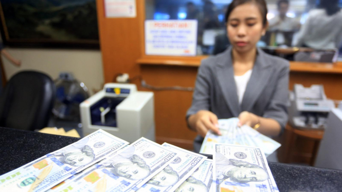 Seorang petugas memperlihatkan pecahan dolar AS yang akan ditukarkan di salah satu gerai penukaran mata uang asing di Jakarta