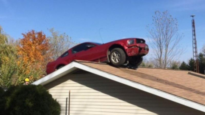 Sebuah mobil Ford Mustang nyangkut di atap rumah