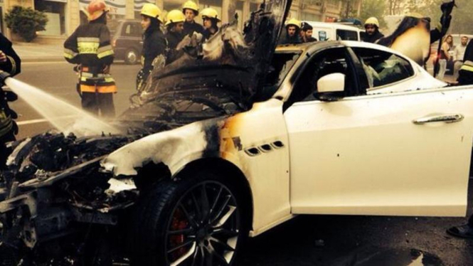 Petugas memadamkan Maserati Quattroporte yang terbakar.