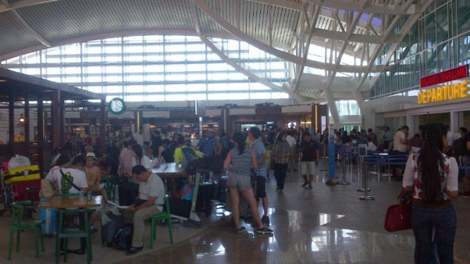 Penumpang beristirahat di Bandara Internasional I Gusti Ngurah Rai. 