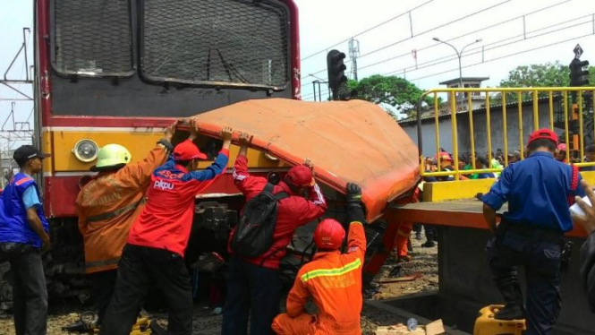 Petugas evakuasi bangkai Metro Mini yang ditabrak KRL di Angke, Jakut.