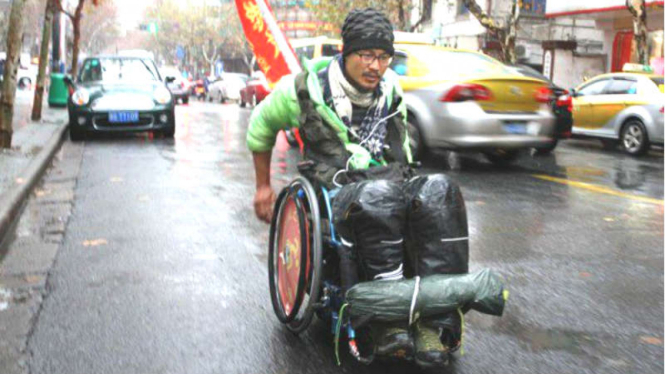 Quan Peng melakukan perjalanan jauh dengan kursi roda.
