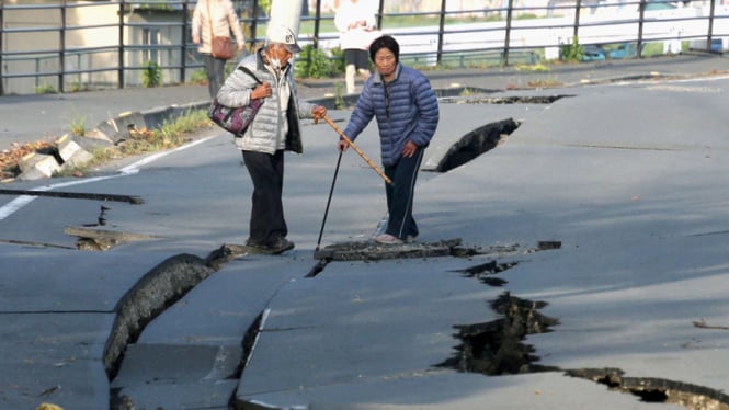 Warga sekitar melihat jalan retak yang diakibatkan oleh gempa di kota Mashiki, prefektur Kumamoto, 16 April 2016.