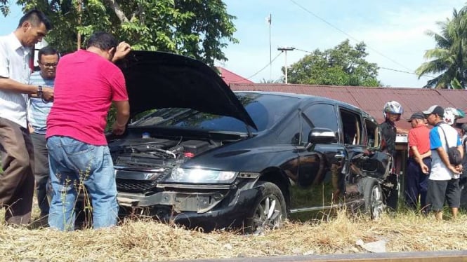 Warga sedang membantu proses evakuasi sedan mewah yang tertabrak kereta api di Sumatera Barat, Selasa (19/4/2016)
