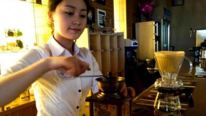 Karyawati sedang mengolah kopi di sebuah kafe