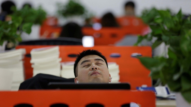 Seorang pekerja kantor di Beijing, China, saat sedang beristirahat. 