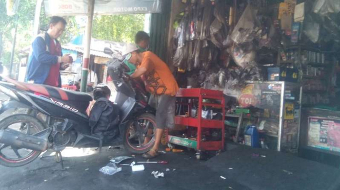 Pengendara servis sepeda motor matiknya.