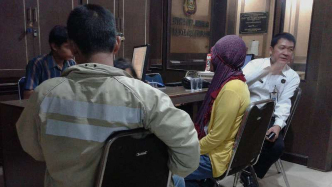 Triani (berbaju kuning) didampingi Ketua KPAID Palembang saat melapor kepada petugas di Markas Polresta Palembang pada Senin, 16 Mei 2016.