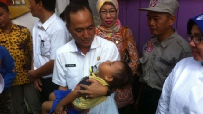 Petugas Dinas Sosial Sumatera Selatan menggendong bayi AL, bocah pemakan batu dan semen. Saat ini perawatan bayi akan ditangani Dinsos setempat.