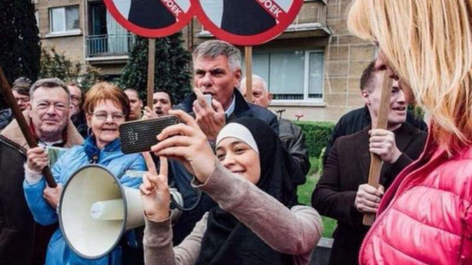 Jilbaber muda ini memilih selfie diantara pemrotes anti Islam di Belgia, Rabu, 18 Mei 2016.