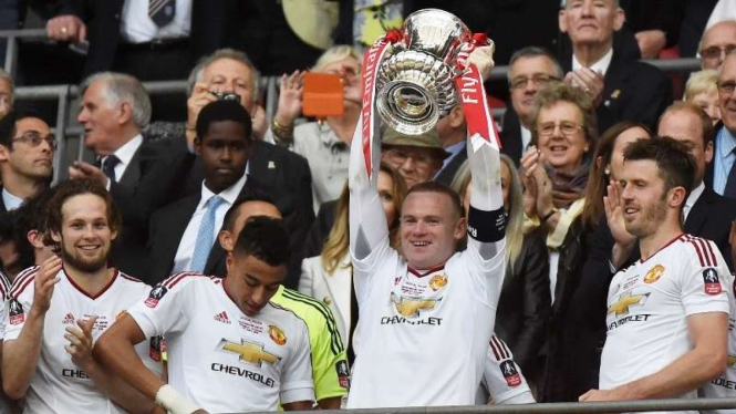 Kapten Manchester United, Wayne Rooney, mengangkat trofi Piala FA.