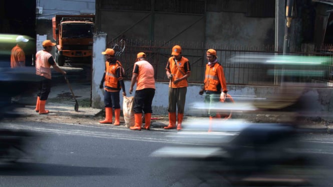 Pasukan oranye Jakarta saat beraksi membersihkan jalan raya dari sampah.