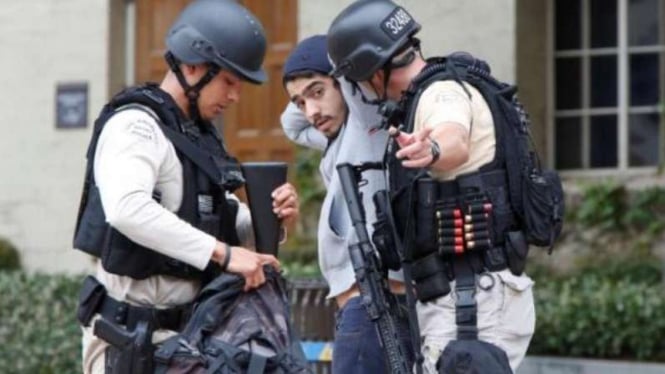Dua petugas polisi Los Angeles sedang menggeledah mahasiswa di kampus UCLA, AS.