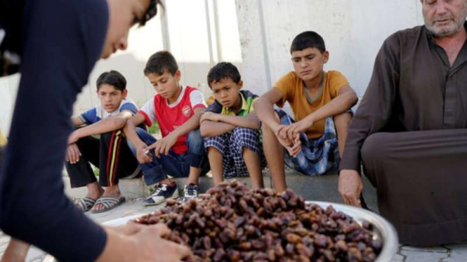 Anak -anak pengungsi Suriah menjual kurma untuk berbuka di kamp pengungsi di Harran, Provinsi Sanliurfa, Turki, Senin, 6 Juni 2016.