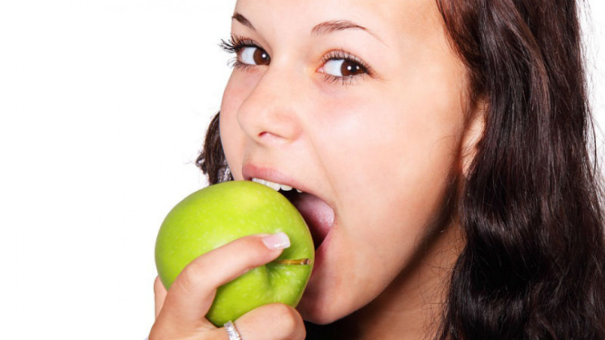 Wanita makan apel.