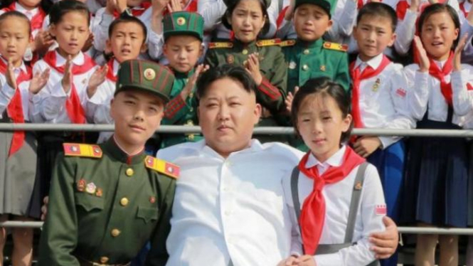 Kim Jong Un rangkul anak-anak di sebuah perayaan.