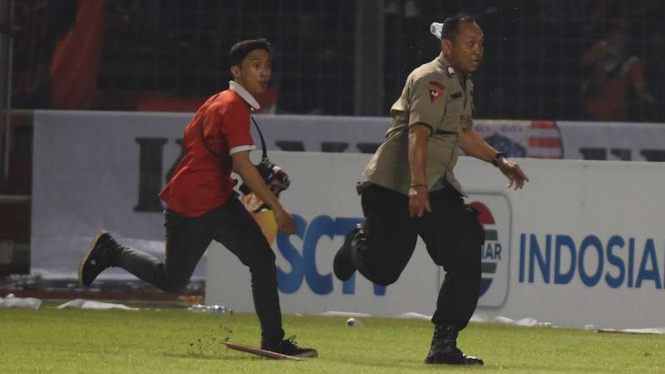 Suporter Persija Jakarta mengejar petugas kepolisian ketika terlibat kericuhan.