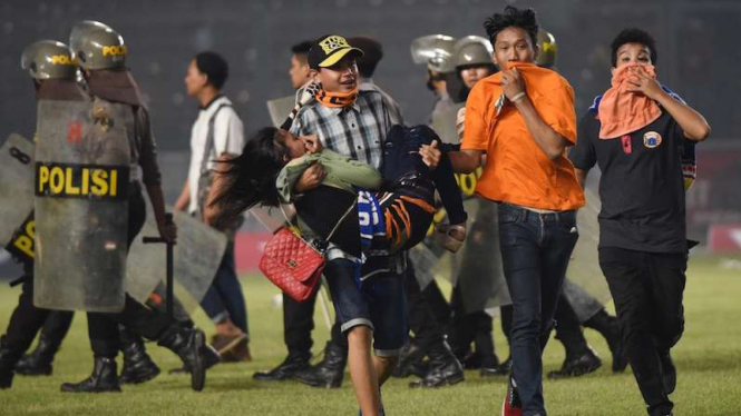 Suporter Persija membopong rekan mereka saat kerusuhan di Stadion GBK Jakarta. 