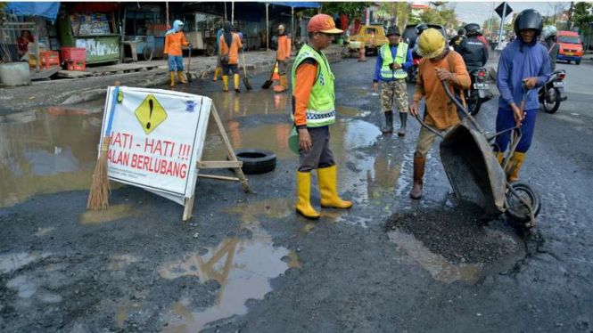  Pekerja melakukan penambalan jalan yang rusak akibat terkena rob di Jalan Kaligawe Semarang, Jateng, Sabtu (25/6/2016).