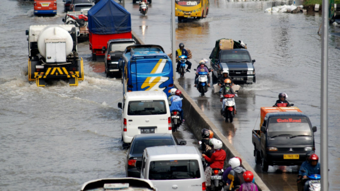 Sejumlah kendaraan melintasi Jalan Kaligawe yang tergenang banjir di Genuk, Semarang, Jawa Tengah, Minggu (3/7/2016). Banjir akibat hujan lebat sejak Sabtu (2/7/2016) malam hingga Minggu dini hari.