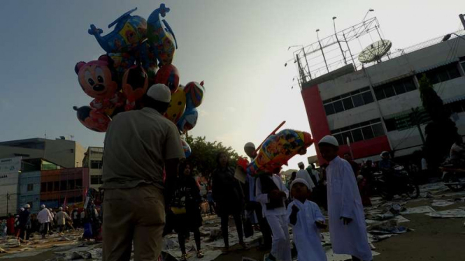 Ade (25), pedagang balon anak-anak saat menjajakan dagangannya kepada calon pembeli di pelataran masjid Agung Kota Palembang, Rabu (6/7/2016)