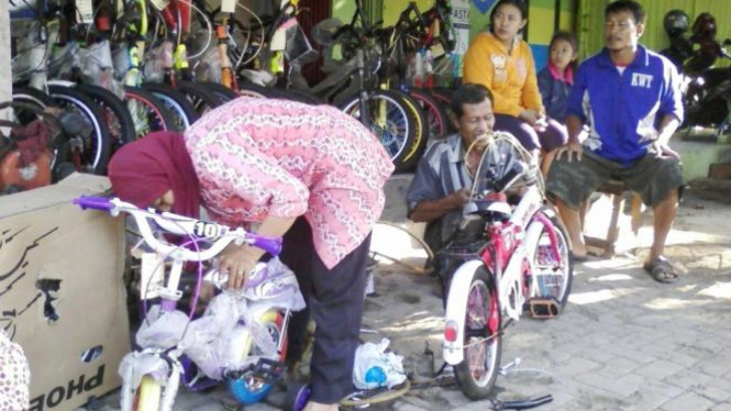 Bu Tumirah dan suami sibuk melayani pembeli sepeda di tokonya. (HCA)