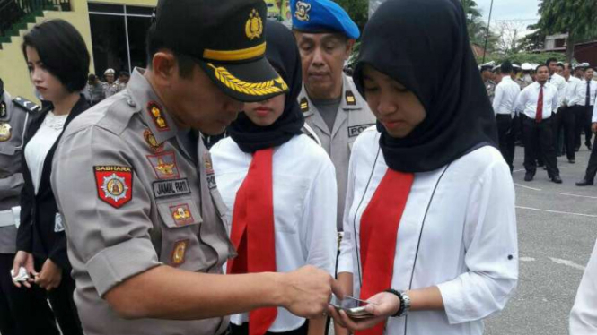 Kapolres Banggai Sulawesi Tengah AKBP Jamal Farti saat melakukan pemeriksaan ponsel milik anggota polisi untuk melarang digunakannya aplikasi Pokemon Go, Senin (25/7/2016)
