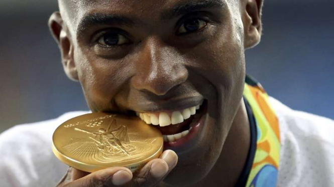 Atlet Britania Raya, Mohamed Farah, menggigit medali emas atletik 10.000 meter.