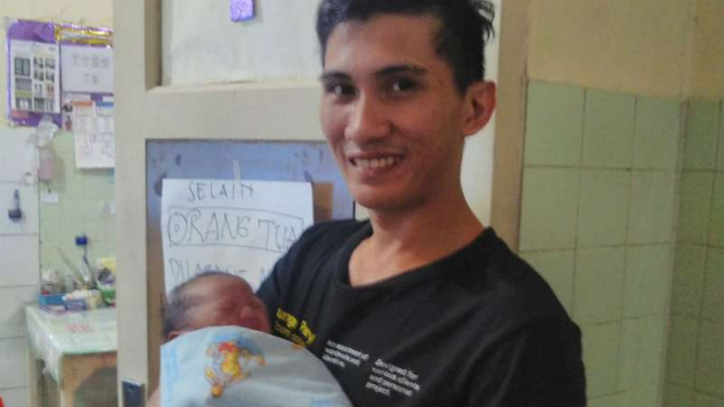 Theodorus Mamile, mengendong anaknya yang lahir pada 17 Agustus 2016 di Manado.