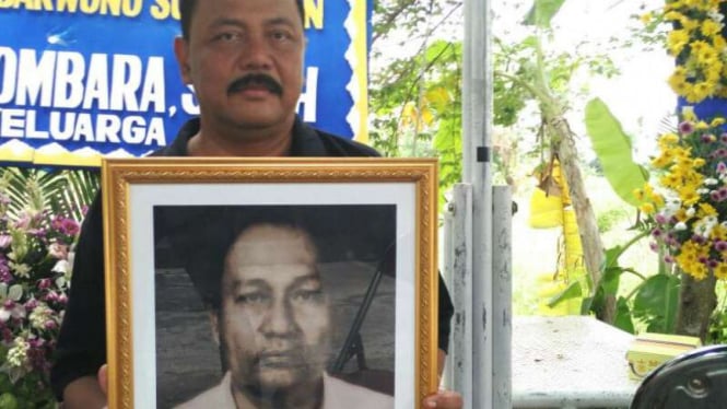 Menantu mendiang Ahmad Tidarwono, Bugiakso, saat membawa foto almarhum di rumah duka.