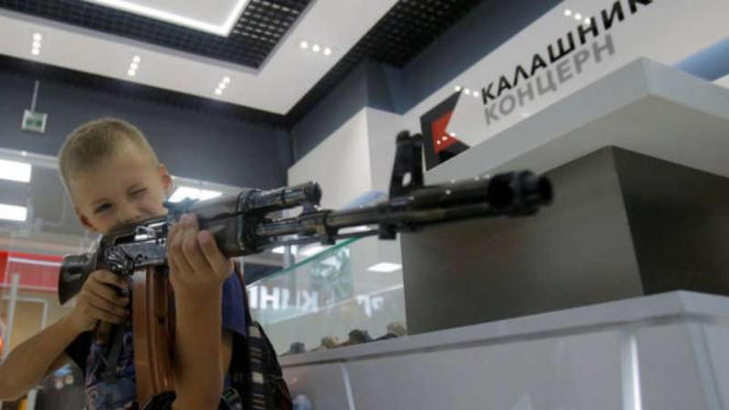 Seorang anak memegang replika AK-47 di toko Kalashnikov, Rusia.