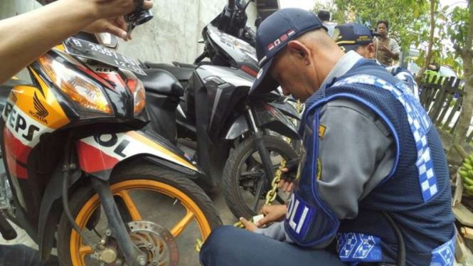 Petugas Dinas Perhubungan, Komunikasi dan Informatika Kota Pontianak menggembok sepeda motor milik pelajar SMP Kota Pontianak, Kamis (1/9/2016)