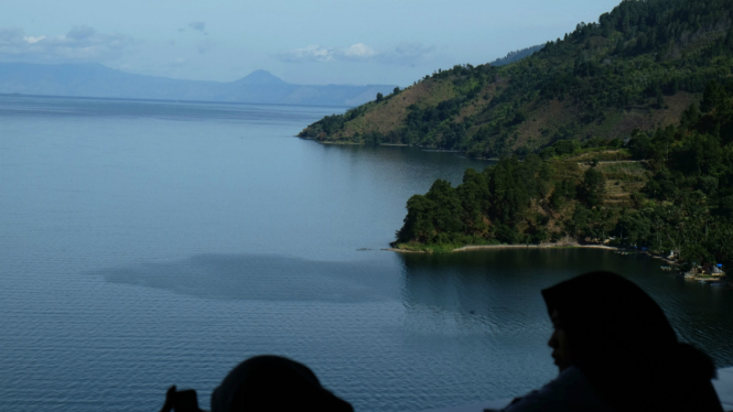 Dua wisatawan melihat panorama Danau Toba tampak dari kawasan Parapat, Simalungun, Sumatera Utara, Senin (22/8/2016). 
