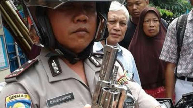 Seorang anggota kepolisian perlihatkan pistol milik begal (ilustrasi).