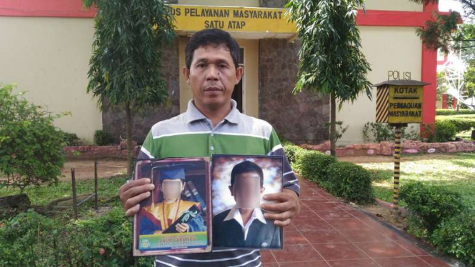  Idris Broji, menunjukkan dua foto anaknya yang diduga menjadi korban pembunuhan dan kekerasan seksual di Mapolda Sumatera Selatan, Rabu (14/9/2016).