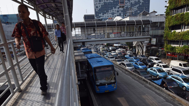 Calon penumpang berjalan menuju Halte Harmoni untuk menaiki bus Transjakarta