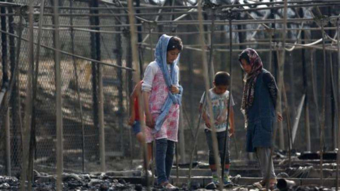 Pengungsi sedang melihat-lihat kamp penampungan yang habis terbakar di Yunani.