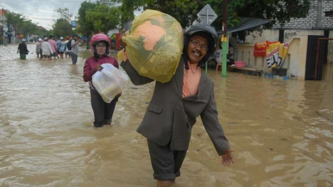 Warga melintasi banjir yang menggenangi Jalan utama di Kabupaten Sampang, Jawa Timur, Minggu (25/9/2016).