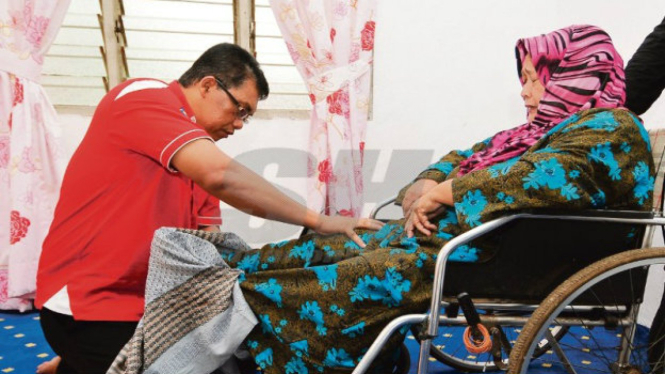 Founder Yayasan Al-Qalam Malaysia, Datuk Seri Baharuddin Abu, tengah mengobati pasien lumpuh.