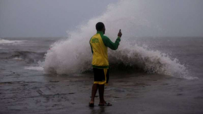 Seorang pria mengambil gambar ombak menjelang terjangan badai Matthew.