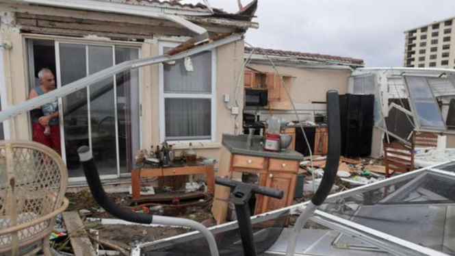 Seorang pria memandang bagian belakang rumahnya yang hancur.