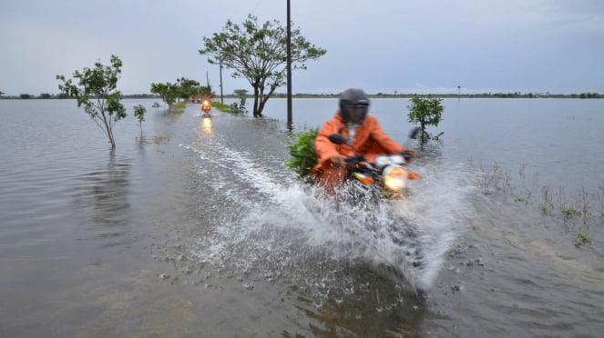 Pengendara sepeda motor melintasi banjir di Kudus