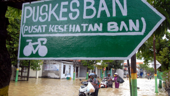Pengendara melintasi banjir yang menggenangi Jalan utama di Kabupaten Sampang