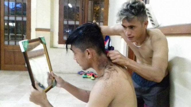 Gelandang Gresik United, M Sidik Saimmima (kanan), saat mencukur rambut Arsyad Yusgiantoro.