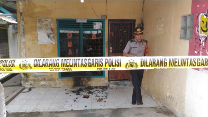 Anggota polisi memasang garis polisi di Salon Omah milik Susanto di Kota Palembang usai dilempar bom molotov oleh orang tak dikenal, Senin (31/10/2016).
