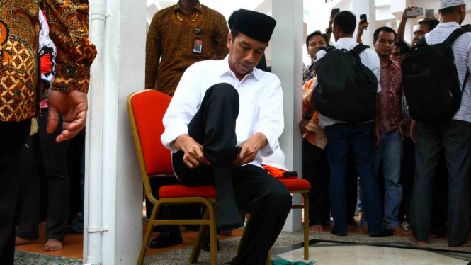 Presiden Joko Widodo memakai sepatunya usai menunaikan Salat Jumat